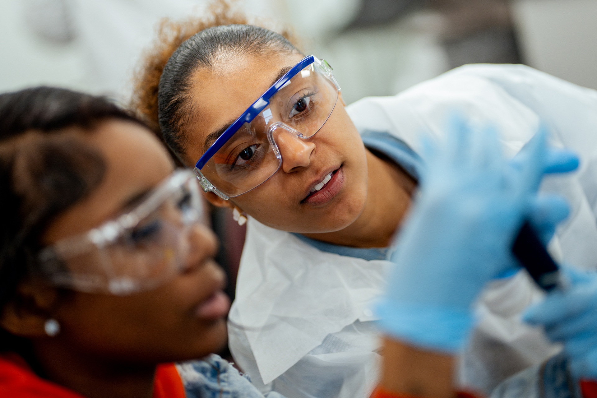 Two participants wearing safety glasses, lab coats, and gloves during a biotech boot camp.