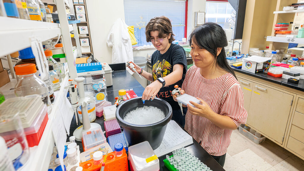 Charlie Saunders working in a research lab with a graduate student.