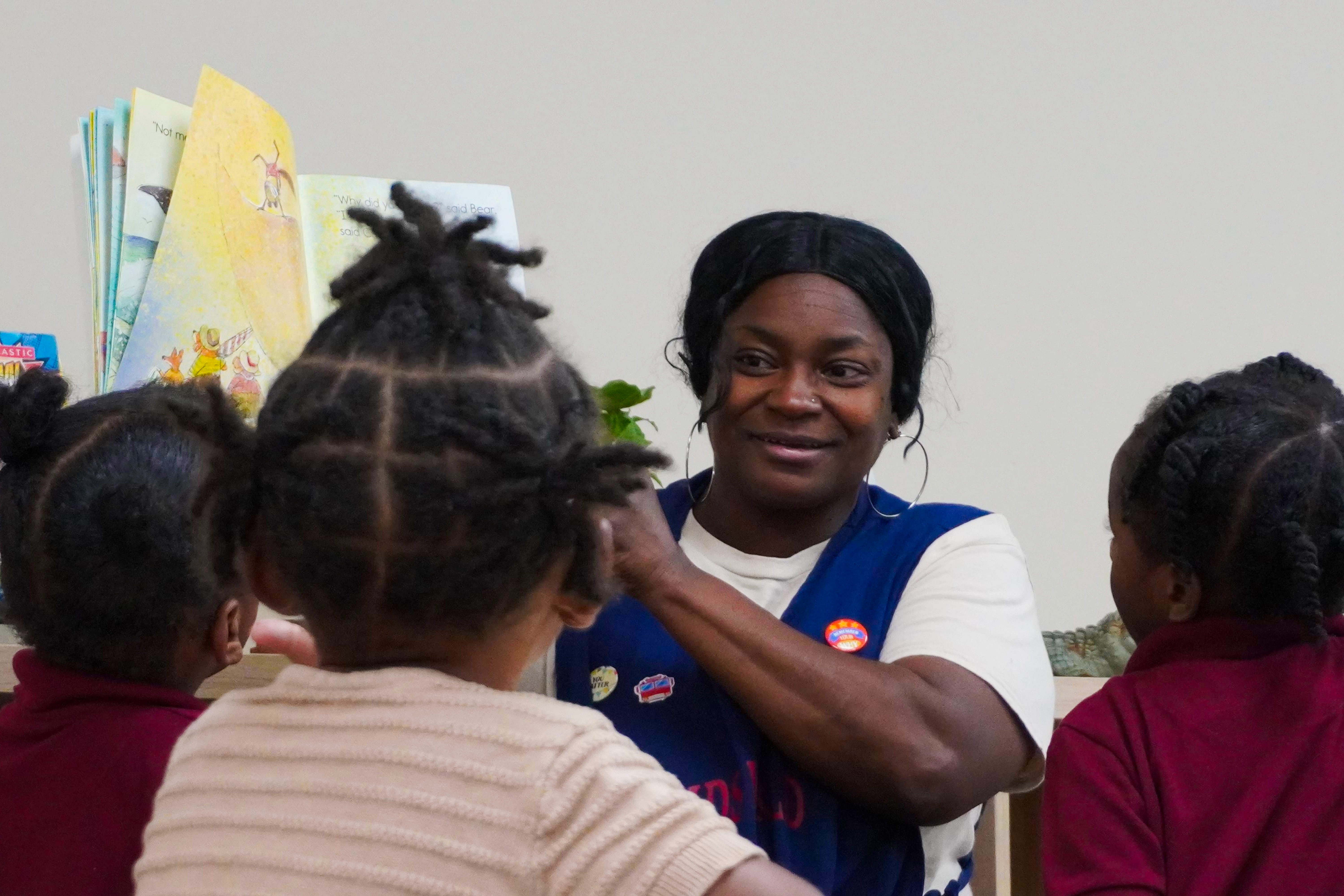 A teacher reads a picture book to several young students.